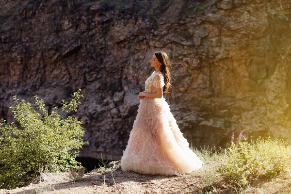 Kayalardan oluşan bir arka planda Boho tarzı elbise giyen modaya uygun genç bir manken. Kadın güzelliği ve tarz kavramı. Reklam ya da kıyafet satışı tasarımı.