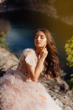 Kayalardan oluşan bir arka planda Boho tarzı elbise giyen modaya uygun genç bir manken. Kadın güzelliği ve tarz kavramı. Reklam ya da kıyafet satışı tasarımı.