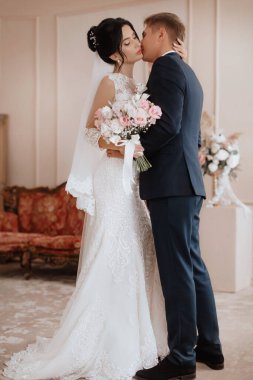 Beautiful young couple, the bride and groom. Luxurious light interior. Wedding day concept