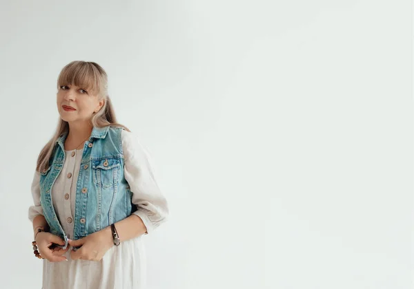 Beautiful elderly woman in a light clothes on a white background with place for text. Portrait senior woman. Elderly lifestyle at home concept. Advertisement or clothes sale design. Mock up for design, clothes shop sale.