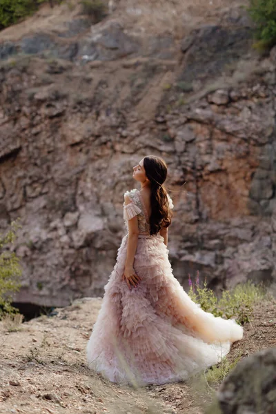 Kayalardan oluşan bir arka planda Boho tarzı elbise giyen modaya uygun genç bir manken. Kadın güzelliği ve tarz kavramı. Reklam ya da kıyafet satışı tasarımı.