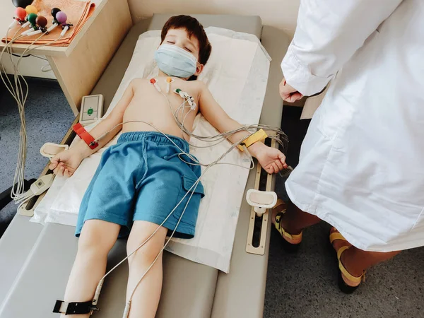 Yıllık terapi muayenesi sırasında bir çocuğun göğsüne elektrokardiyogram uygulamak. Kalp hastalığının teşhisi Stok Resim