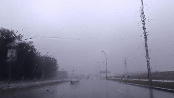 Sakta i backarna. Regndroppar tvättar bort vindrutetorkare av bil på molnig regnig dag på vägen — Stockvideo