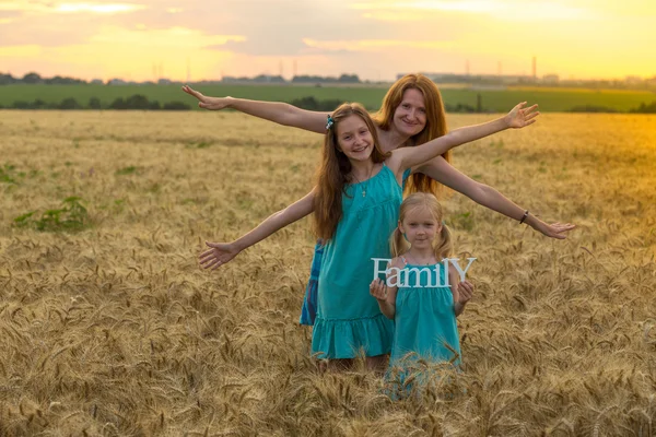 Mother with daughters on wheat field — Stock Photo, Image