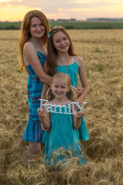 Mother with daughters on wheat field — Stock Photo, Image