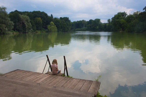 Chica triste en una orilla del río — Foto de Stock