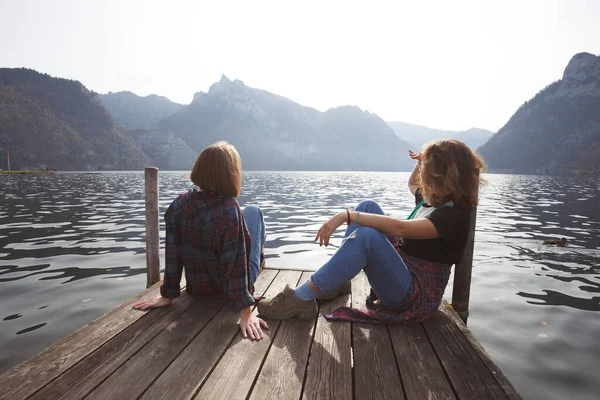 Dvě Dospívající Usměvavé Dívky Posezením Molu Břehu Jezera Hory Pozadí — Stock fotografie