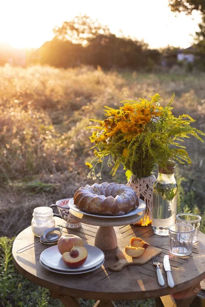 garden and still life. tea party in the garden -  peach pie, vase with bouquet of wildflowers on a tabl