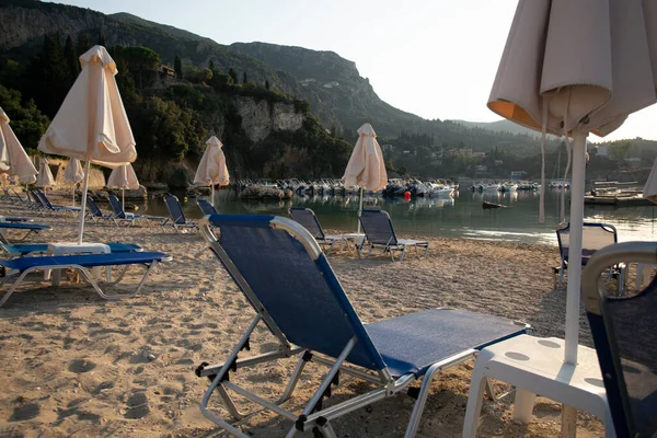海の海岸にある傘とサンラウンジャーです ギリシャのPaleokastritsa湾 — ストック写真