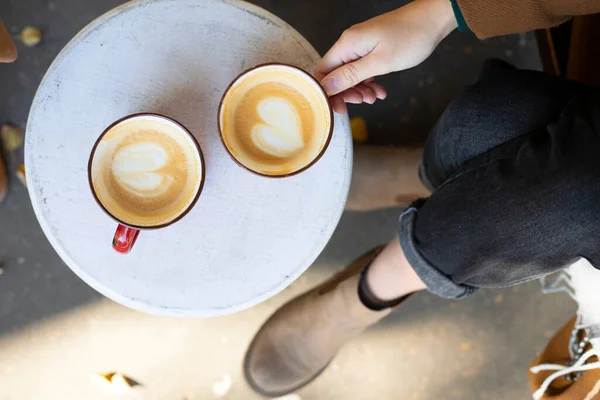 Zwei Rote Tassen Kaffee Auf Dem Tisch Und Die Beine — Stockfoto