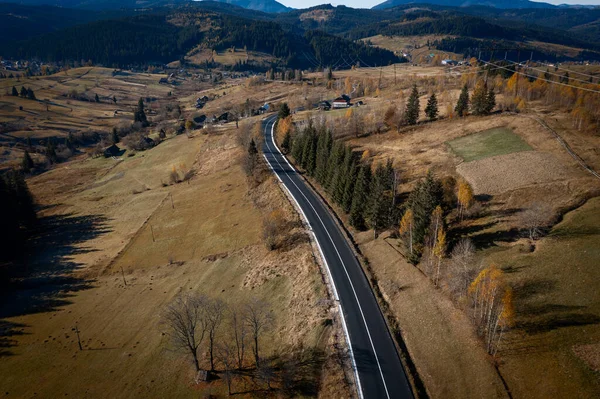 山の村のカラフルな空中景観と秋の緑の丘の美しい曲がりくねった道 — ストック写真