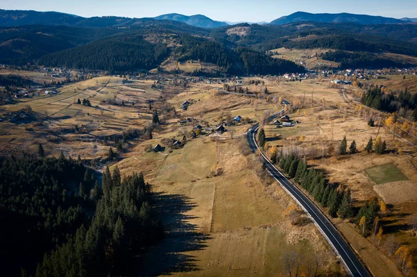 山の村のカラフルな空中景観と秋の緑の丘の美しい曲がりくねった道 — ストック写真