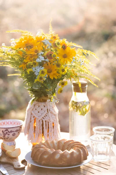 garden and still life. tea party in the garden -  peach pie, vase with bouquet of wildflowers on a tabl