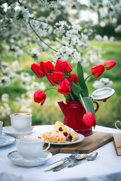 steel life - breakfast in the spring garden. table with white tablecloth served for tea drinkin