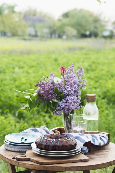 garden and still life. tea party in the garden -  pie, vase with bouquet of lilac on a tabl