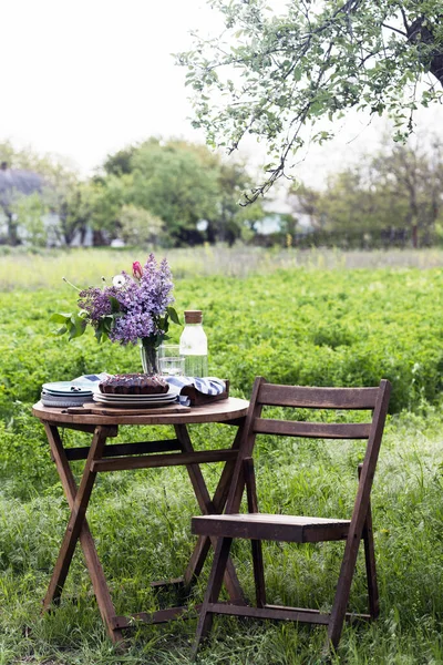 garden and still life. tea party in the garden -  pie, vase with bouquet of lilac on a tabl