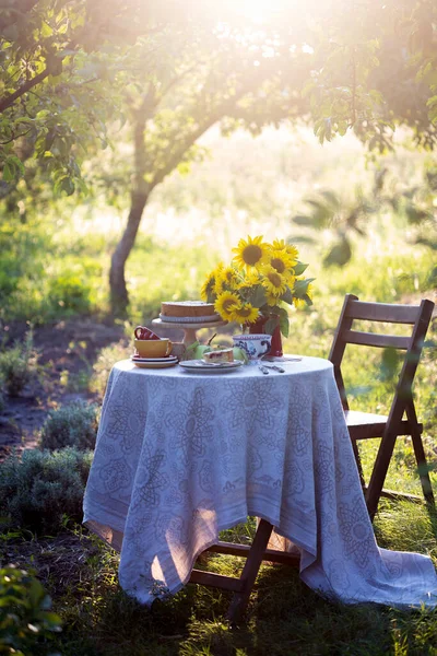 garden and still life. tea party in the garden - pie, vase with sunflowers and apples on a table