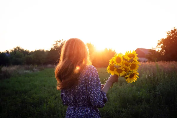 girl holding a huge bouquet of sunflowers in their hands in the sunset ligh