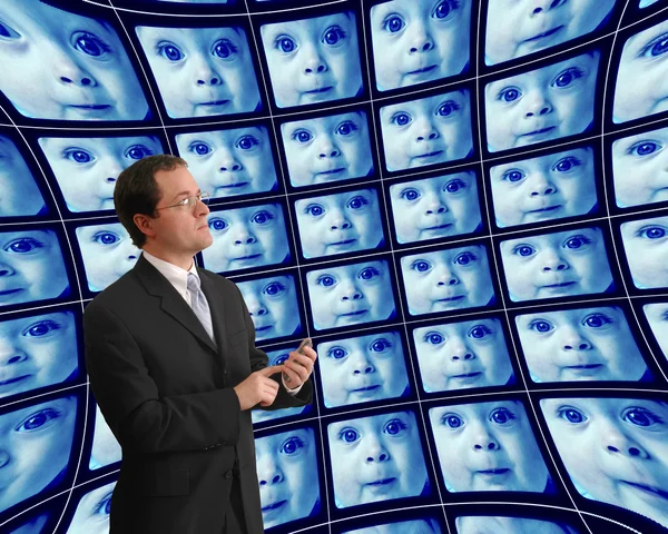 Man in suit monitoring babies on distorted video screens — Stock Photo, Image