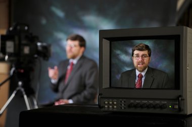 Monitor in TV production studio showing man talking to a camera clipart