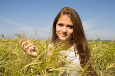 Freckled girl in a field with spikelets clipart