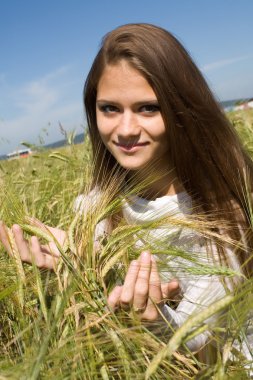 Freckled girl in a field with spikelets