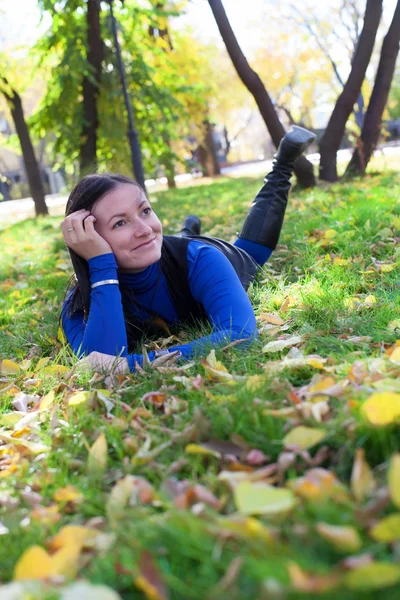 Tyttö makaa nurmikolla puistossa — kuvapankkivalokuva