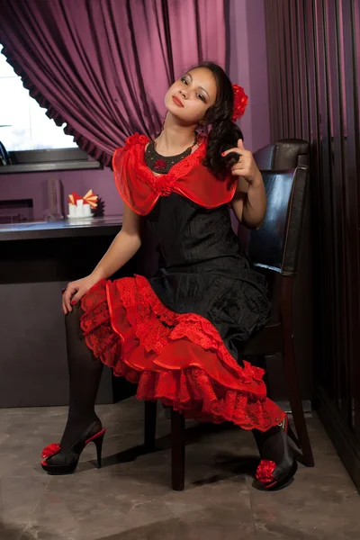 Chica joven en un vestido brillante sentado en una silla — Foto de Stock