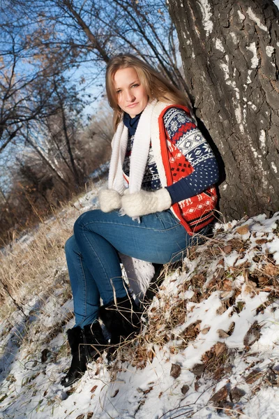 Chica en el bosque de invierno se sienta debajo de un abedul — Foto de Stock