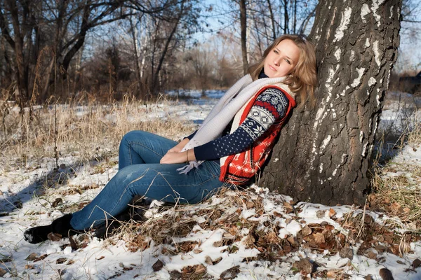 Menina sentada debaixo de uma bétula em uma floresta de inverno — Fotografia de Stock