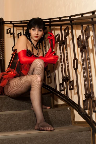 Morena en corsé rojo sentada en las escaleras — Foto de Stock