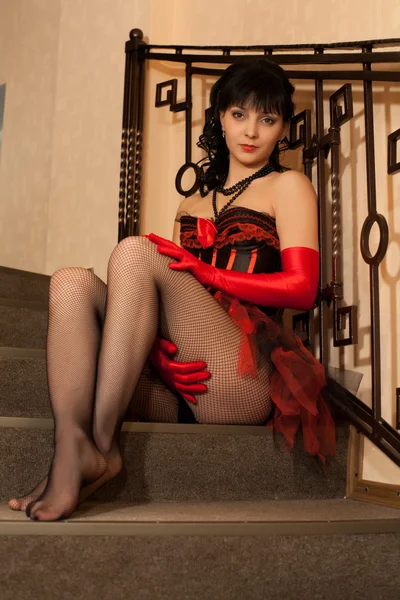 Morena em espartilho vermelho sentado nas escadas — Fotografia de Stock