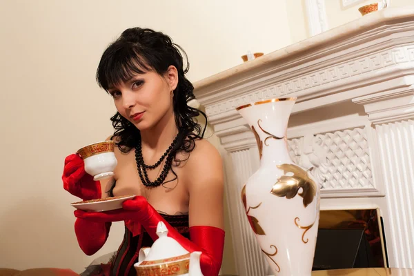 Young brunette drinking tea while sitting by the fireplace — Stock Photo, Image