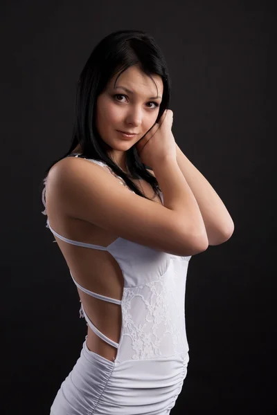 Brunette in een witte jurk op een zwarte achtergrond — Stockfoto