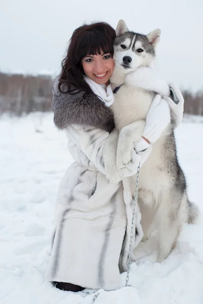 Brunette with dog in winter forest — Stock Photo, Image