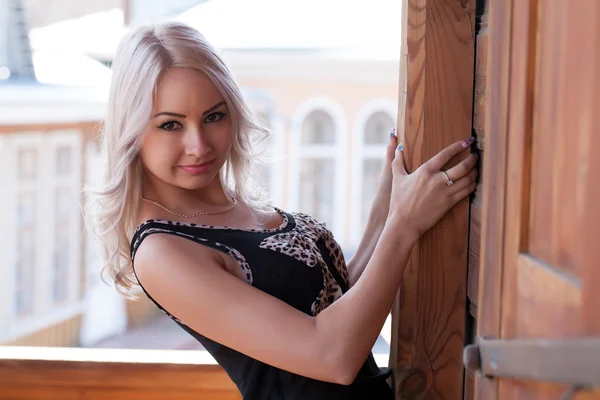 Яркая блондинка на балконе деревянного особняка — стоковое фото
