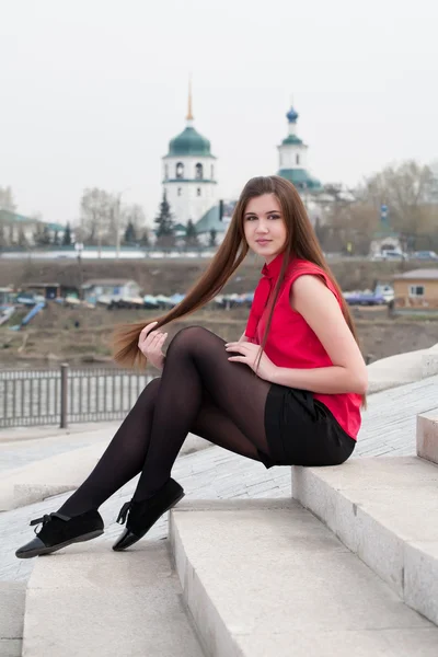 Menina bonita sentada nas escadas no fundo da cidade — Fotografia de Stock