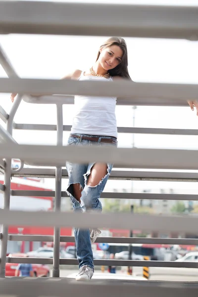 Girl in jeans and a t-shirt on the background of metal structures — Stock Photo, Image