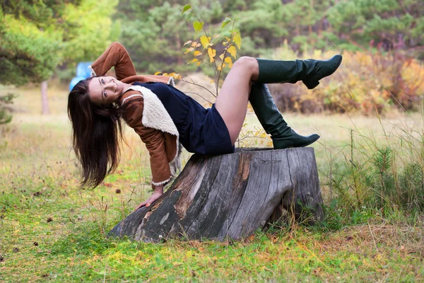 Девушка, сидящая в лесу на большом пне — стоковое фото