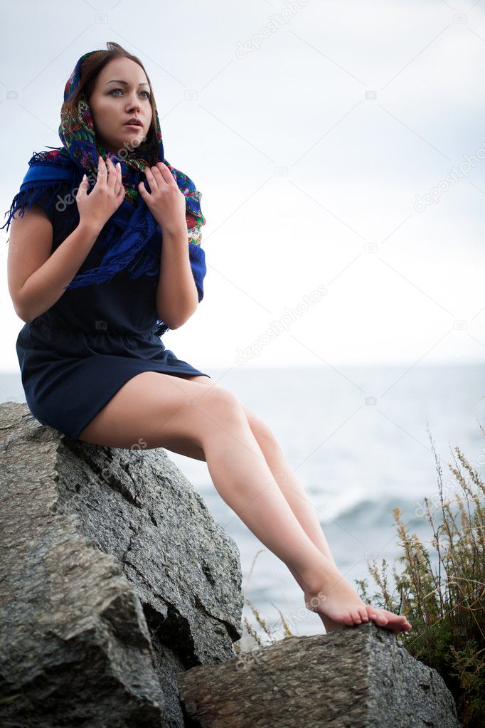 Young girl sitting on the shore of Lake Baikal