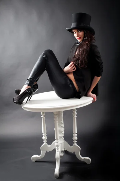 Dziewczyna w kapeluszu siedzi na stole — Zdjęcie stockowe