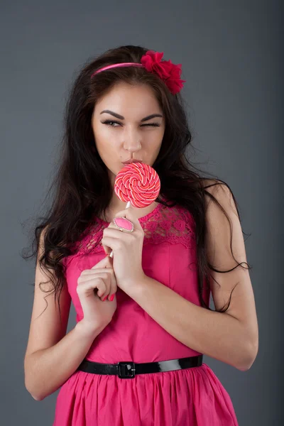 Meisje in een roze jurk bedrijf een lolly — Stockfoto