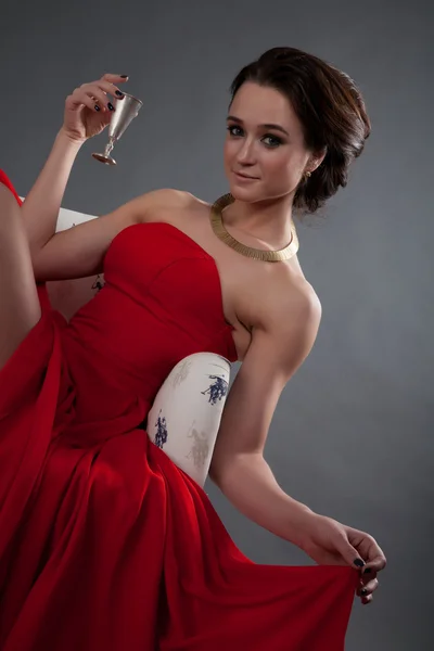 Beautiful girl in red evening dress sitting in a chair — Stock Photo, Image