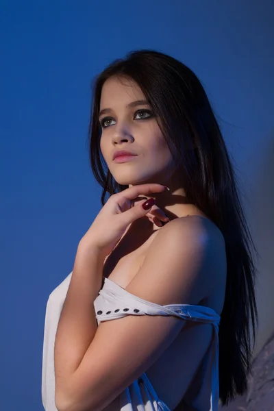 Retrato de una joven hermosa chica con luz de fondo azul — Foto de Stock