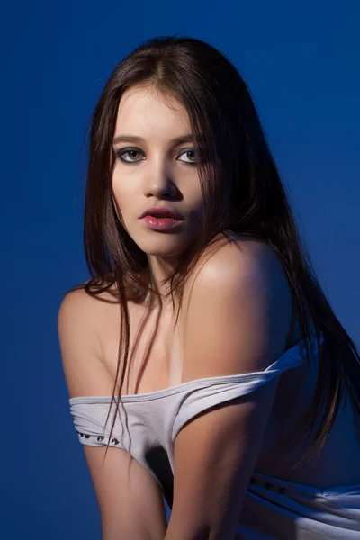 Retrato de uma jovem menina bonita com luz de fundo azul — Fotografia de Stock