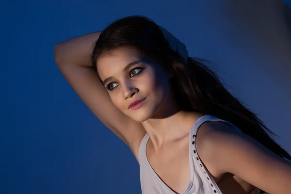 Porträt eines jungen schönen Mädchens mit blauer Hintergrundbeleuchtung — Stockfoto