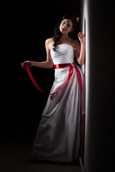 Bride in a white dress with a red ribbon — Stock Photo, Image