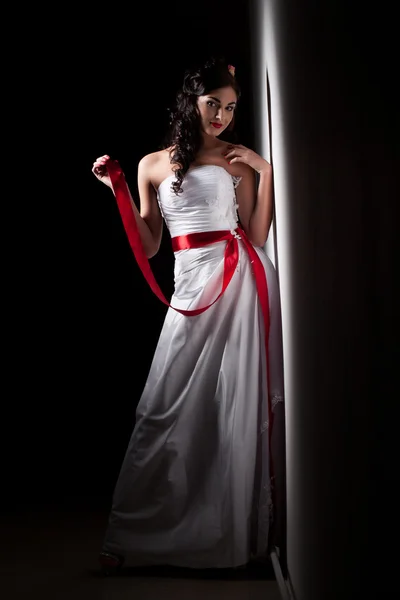 Bride in a white dress with a red ribbon — Stock Photo, Image