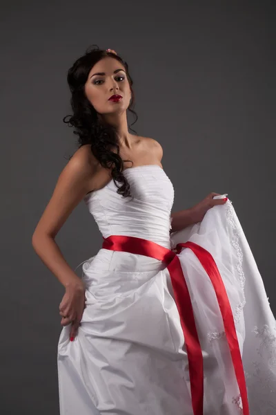 Bride in a white dress with a red ribbon — Stock Photo, Image