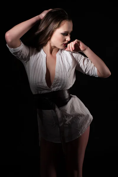Estúdio retrato de uma bela jovem em uma camisa branca em um fundo preto — Fotografia de Stock